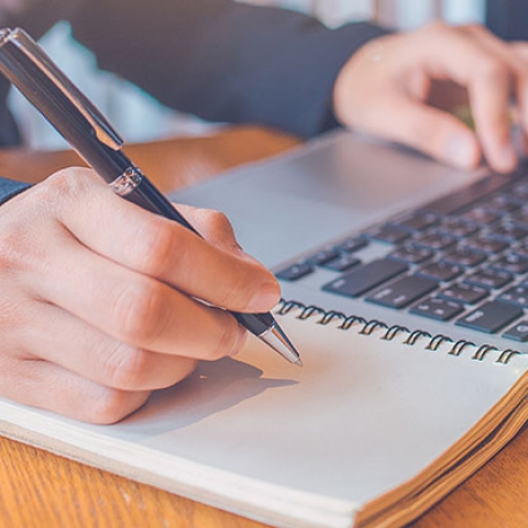 Person working on a laptop and taking notes