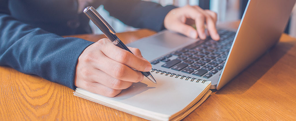 Person working on a laptop and taking notes