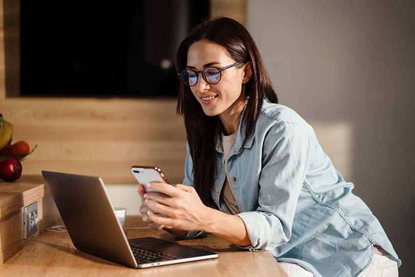 Woman with mobile device and laptop